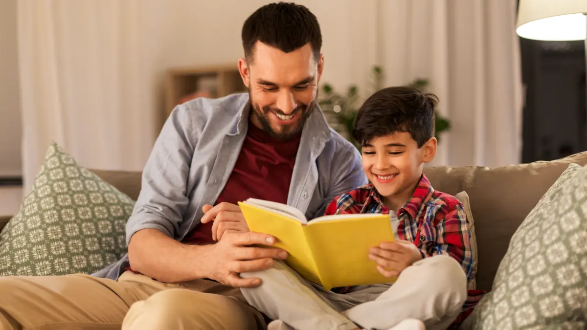 Un padre che legge un libro con il figlio in lingua inglese