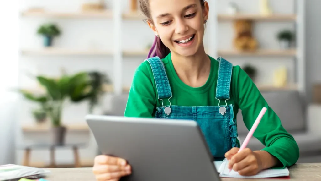 Studente che prende appunti su un tablet durante un corso di inglese online da casa.